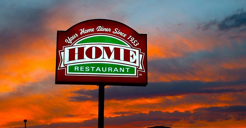 an illuminated restaurant sign at sunset